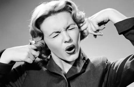 A black & white picture of a woman, from around the 1950s, with her eyes shut tight and her fingers in her ears, her mouth is open as if she was say "No, no, no! I don't want to know this!"